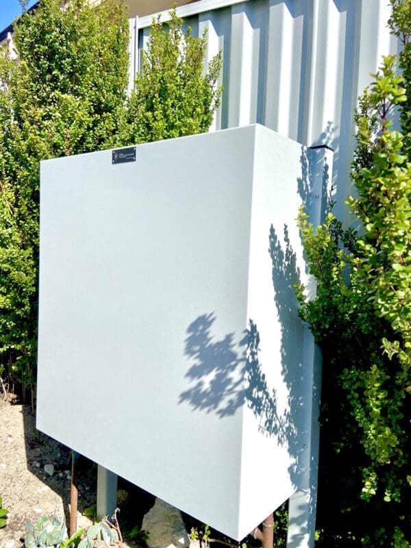 White home filtration system mounted on a metal fence with trees