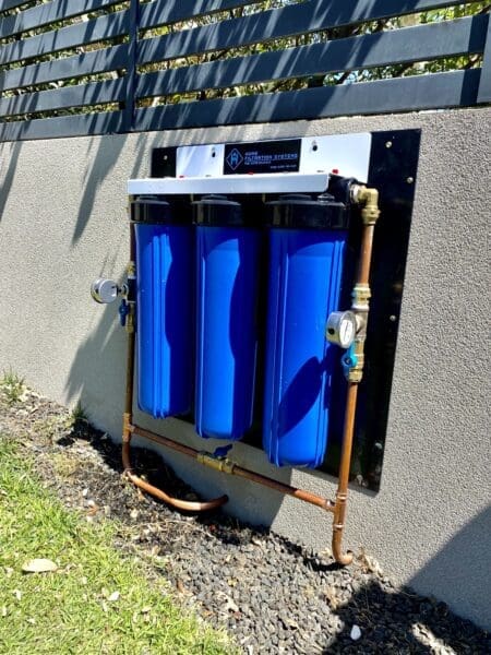 Open filtration system mounted on a concrete wall with filters exposed.