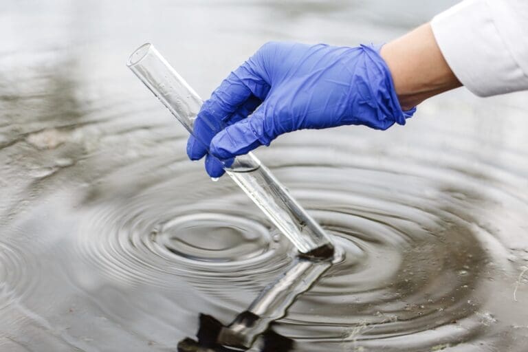 Hand with glove and science tube showing contaminates water with microplastics